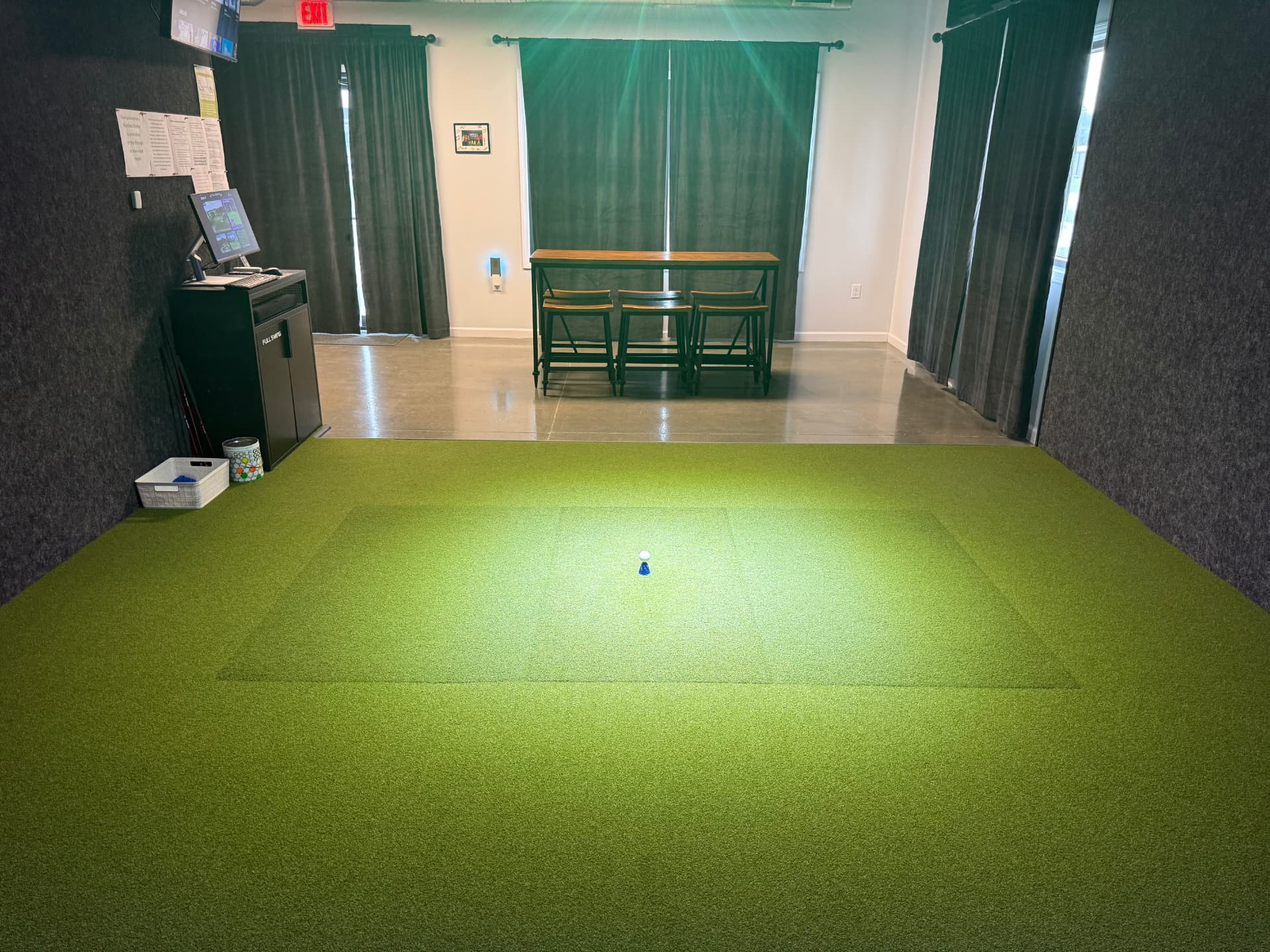 Wide view of the turf hitting area and lounge seating at Swing 365 Beatrice